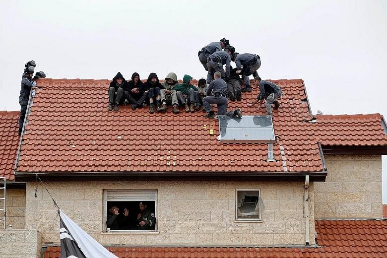 Israeli police removing pro-settlement activists from a roof yesterday. Israeli forces were carrying out a court order to demolish nine houses built illegally on privately owned Palestinian land in the Israeli settlement of Ofra, in the occupied West