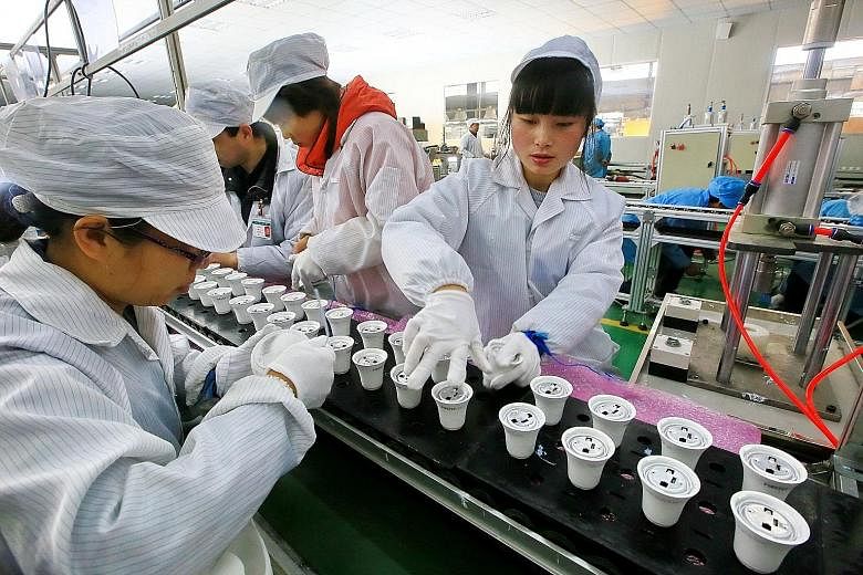 Workers assemble light bulbs at a factory in Suining in south-west China. Factory activity in China expanded faster than expected last month as domestic and export demand picked up. It is the seventh consecutive month that China's manufacturing PMI w