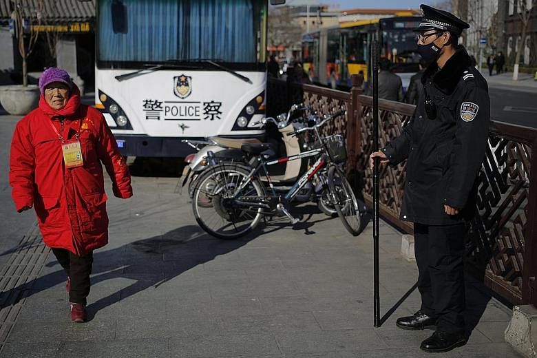 A public security volunteer and a security guard in Beijing yesterday. Security has been beefed up in the Chinese capital ahead of the country's annual parliamentary and consultative sessions.