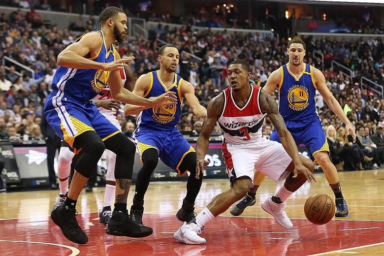 Washington Wizards guard Bradley Beal dribbles as three Warriors - JaVale McGee (left), Stephen Curry (centre) and Klay Thompson - close down the space at Verizon Centre.