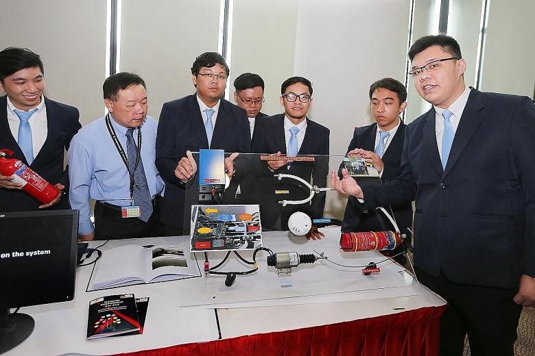 ITE lecturer Pang Tyng Fa (in blue), with his students (from left) Oscar Pong, Willy Tho, Dominic Yeo, Muhammad Irsyad Amin S., Stanley Ng and Tan Yi Ying, presenting the team's vehicle fire-suppression system yesterday. The automotive engineering st