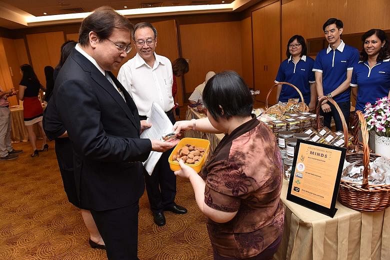 OCBC group chief executive Samuel Tsien getting a cookie at a booth set up by the Movement for the Intellectually Disabled of Singapore (Minds) at the launch of the bank's expanded CSR programme yesterday, as Minds CEO Keh Eng Song looks on.