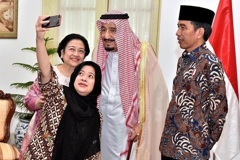 Saudi Arabia's King Salman posing with former Indonesian president Megawati Sukarnoputri and her daughter Puan Maharani on Thursday at the presidential palace in Jakarta, as President Joko Widodo looks on.