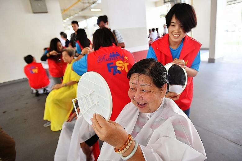 Madam Tay Noi Moi, 73, checking her hair after having it cut by Ms Yee Naung Htwe, 31, a student hairdresser from Myanmar. About 150 volunteers were at yesterday's community event in Ang Mo Kio, giving haircuts and manicures to underprivileged senior