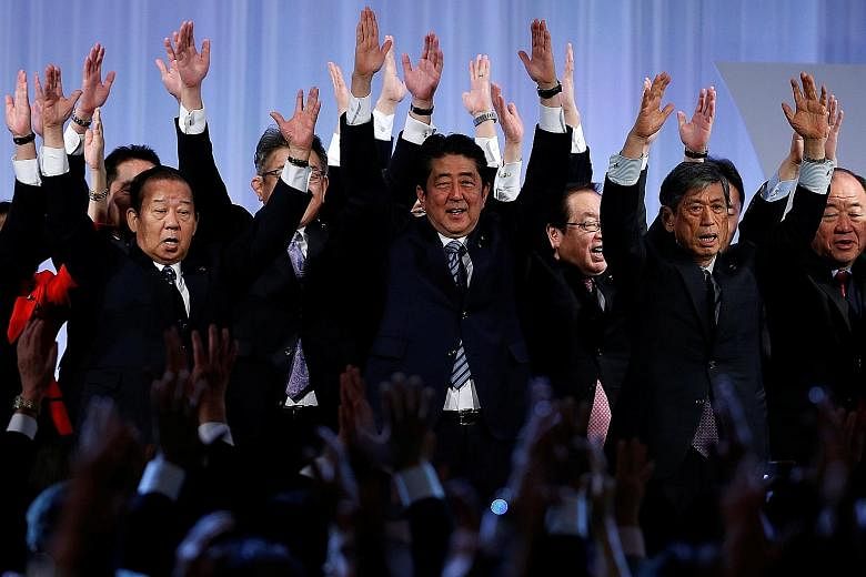 Mr Shinzo Abe (centre) cheering with members of the ruling Liberal Democratic Party during its annual party convention in Tokyo yesterday. The LDP congress has approved extending the limit for its leaders to three consecutive three-year terms, up fro