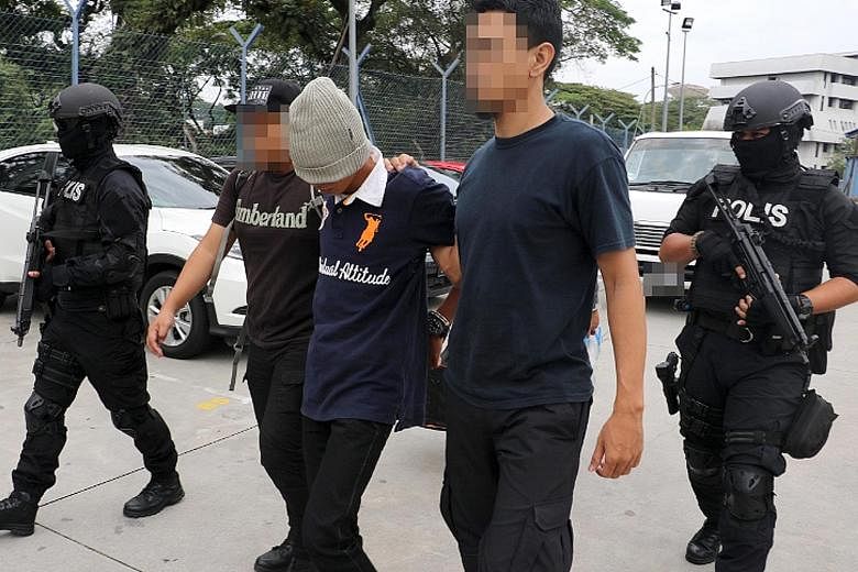 Police leading away a suspect linked to terror groups during a raid in the Klang Valley last month.
