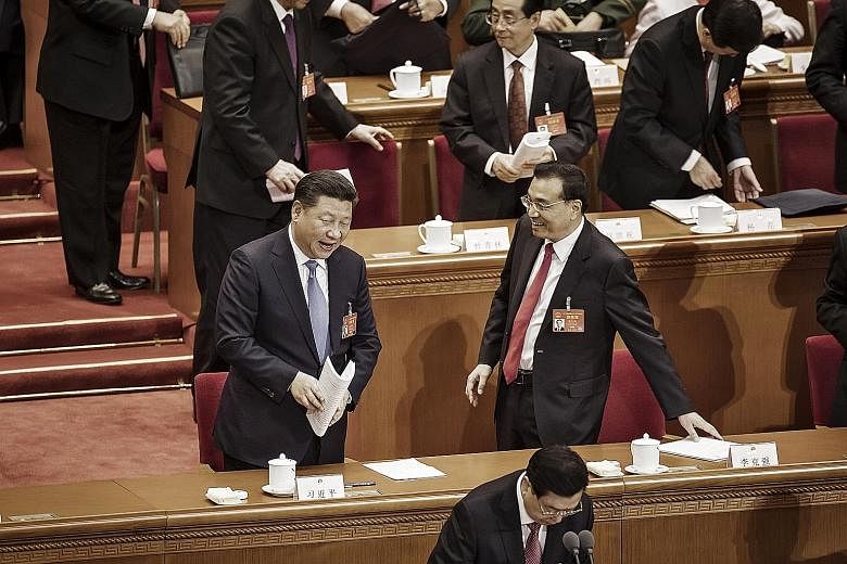 Chinese President Xi Jinping (left) speaking with Premier Li Keqiang following the opening of the National People's Congress, China's Parliament, at the Great Hall of the People in Beijing yesterday. Mr Xi said yesterday that China would continue to 