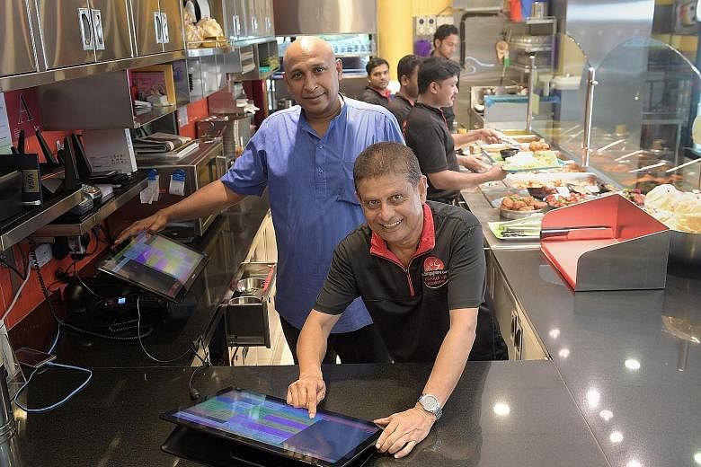 Mr Raveenthiran Thangavelu (in blue shirt), owner of The Singapore Curry by Velu's, said it was not easy convincing his staff that using technology would work. But his staff, including waiter Anwar Aziz Marican, have embraced the changes, which have 