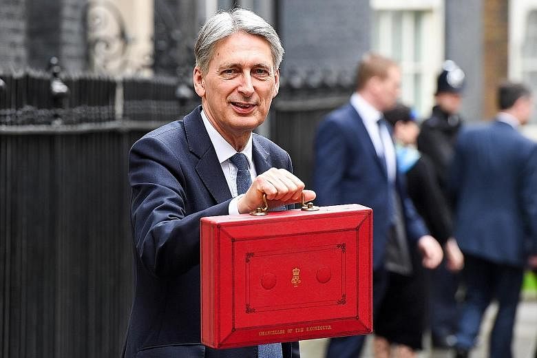 Mr Hammond toting the Budget in a briefcase as he leaves his official residence at 11 Downing Street to present his first Budget statement. He says the fiscal plan lays the foundation for "a stronger, fairer, more global Britain".