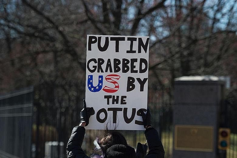 A protester outside the Russian Embassy in Washington, DC, with a sign that refers to Russian President Vladimir Putin's alleged hand in the US election and Mr Donald Trump's boast of groping women.