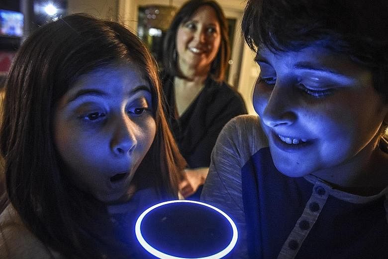 Asher Labovich, 13, and his sister, Emerson, 10, using the family's Alexa, an Amazon Echo voice assistant. Their mum, Mrs Laura Labovich, is in the background.