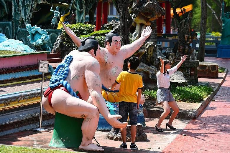 Visitors posing for photographs with statues at Haw Par Villa last Friday. Construction to upgrade its infrastructure and facilities is under way at the 80-year-old park, in a bid to improve visitorship.