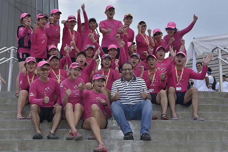 Above: Children learning how to play volleyball at the Sports Hub as part of the Community Play Day yesterday. Left: Minister for Trade and Industry (Industry) S. Iswaran with pink-clad paddlers who represent breast cancer survivors and supporters.