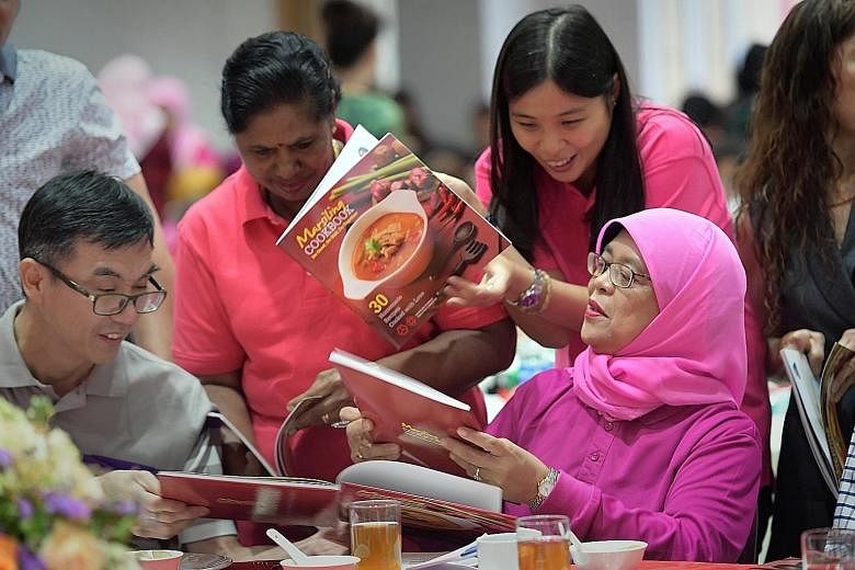 Madam Halimah signing copies of the Marsiling Cookbook at the International Women's Day celebration at Marsiling Community Club yesterday. The book, which has more than 30 recipes, including one by her, raised $26,000 for the Marsiling Independent Mu