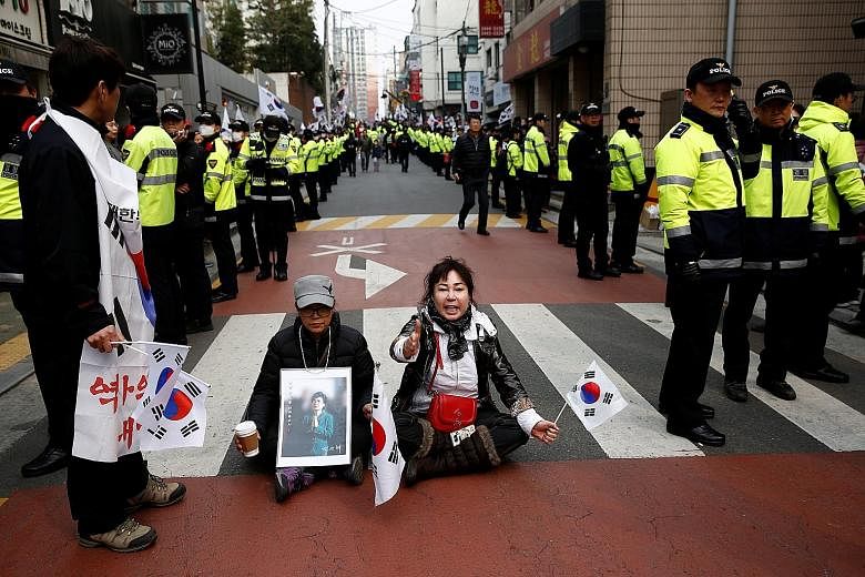 Ms Park's supporters staging a sit-in outside her private home in Seoul to block a media vehicle while awaiting her arrival yesterday. Mr Moon received the highest approval rating among a group of presidential hopefuls, according to a weekend poll. H