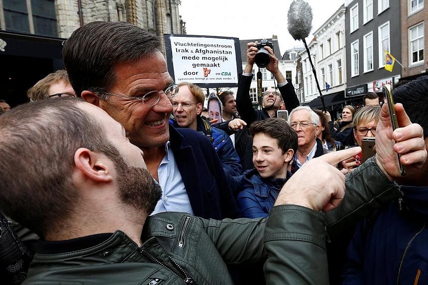 The latest polls show Prime Minister Mark Rutte's party slightly ahead for Wednesday's general election. A supporter snapping a selfie with far-right populist Geert Wilders, who wants to take the Netherlands out of the EU, ban immigrants from Muslim 
