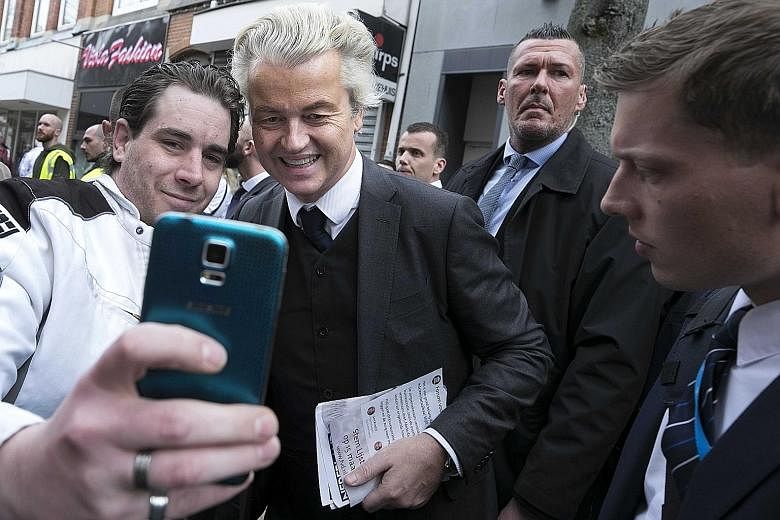 The latest polls show Prime Minister Mark Rutte's party slightly ahead for Wednesday's general election. A supporter snapping a selfie with far-right populist Geert Wilders, who wants to take the Netherlands out of the EU, ban immigrants from Muslim 