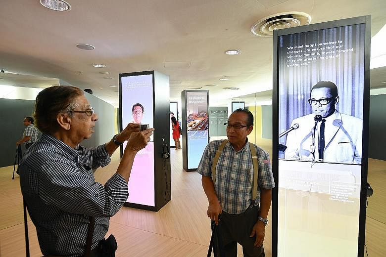Retiree Maurice Peter Anthony, 78, taking a photograph of his friend Freddy Lim, 68, in front of the display on Mr Othman Wok at the showcase at Gardens by the Bay's Waterview Room yesterday.