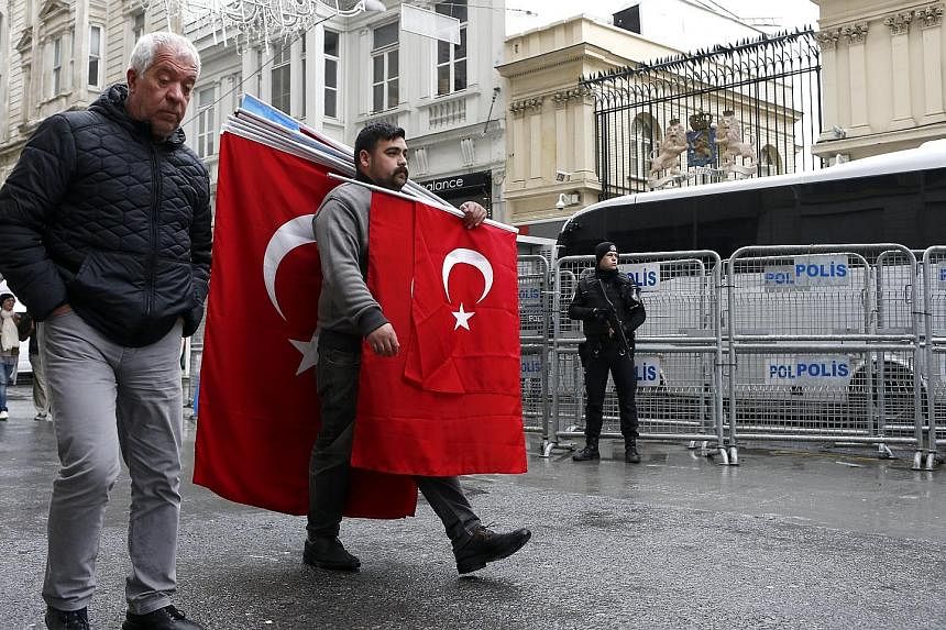 A man with Turkish flags passing a Turkish riot policeman in front of the Dutch consulate in Istanbul yesterday. Tensions between Turkey and the Netherlands escalated after a ban was enforced on Turkish ministers at political events in Rotterdam. Ank