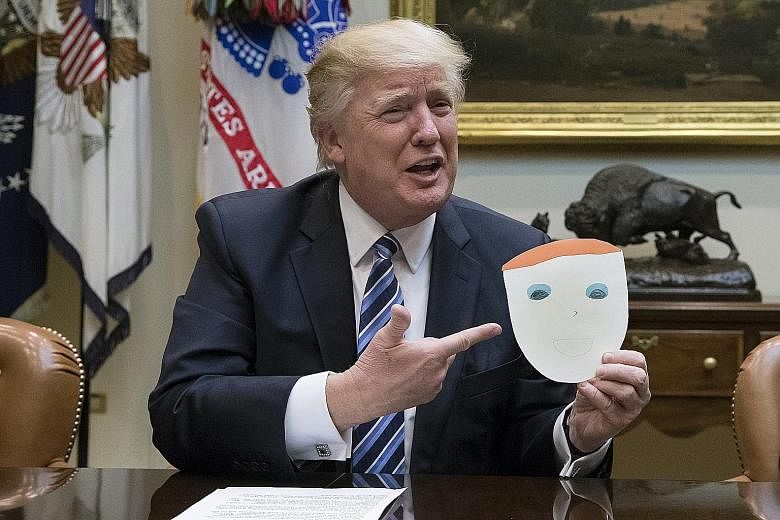 Mr Trump with a drawing done by a child of one of the attendees of a meeting on healthcare in the White House on Monday. The CBO report on the Republican plan to dismantle Obamacare has dealt a potential setback to Mr Trump's first major legislative 