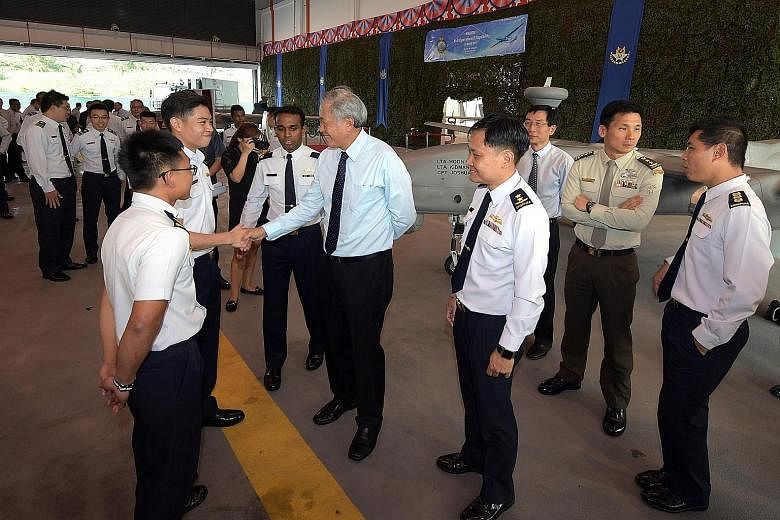 Dr Ng Eng Hen greeting Lieutenant Marcus Chia yesterday. Looking on are (from left) Lieutenant Kidmann Goh, Major John Samuel and Chief of Air Force Mervyn Tan. Behind them is a Heron 1. Dr Ng said the use of NSFs as UAV pilots is a "significant firs