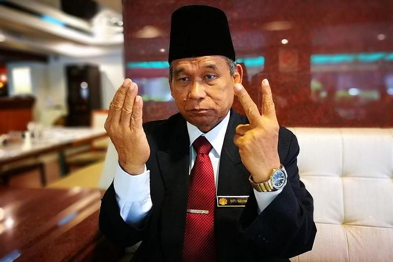 Self-styled Raja Bomoh Ibrahim Mat Zin shows how he prays for Malaysia's protection against North Korea, holding up two fingers to bless both nations.