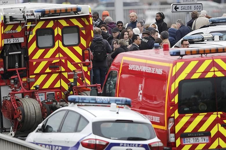 From top: A woman being kept warm under a rescue blanket was among the thousands who were forced to evacuate the Orly-Sud terminal after the shoot-out yesterday. Emergency workers rushed in to provide medical assistance, even as stranded passengers w