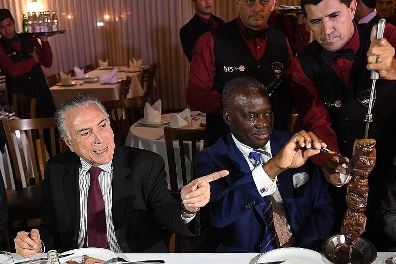 Mr Temer with Angola's Ambassador Nelson Manuel Cosme at a restaurant in Brasilia on Sunday. Nineteen envoys accepted the Brazilian leader's invitation to a steak dinner in a show of faith in the country's meat.