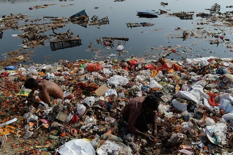 This file photo taken on Oct 12 last year shows scavengers looking for coins and other items among the religious offerings piled up in the badly polluted Yamuna River in New Delhi.