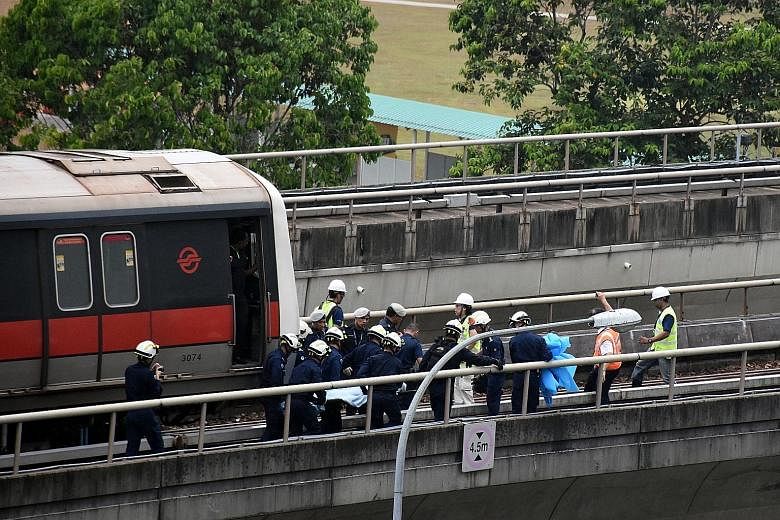 Paramedics from the Singapore Civil Defence Force retrieving the body of one of the two SMRT maintenance staff who were killed in the accident along the train track near Pasir Ris MRT station on March 22 last year.