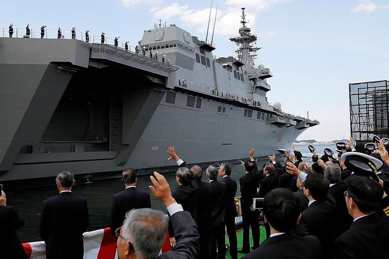 Japanese defence ministry officials seeing off the Kaga, the country's second Izumo-class helicopter carrier, after a handover ceremony at the Japan Marine United shipyard in Yokohama yesterday.