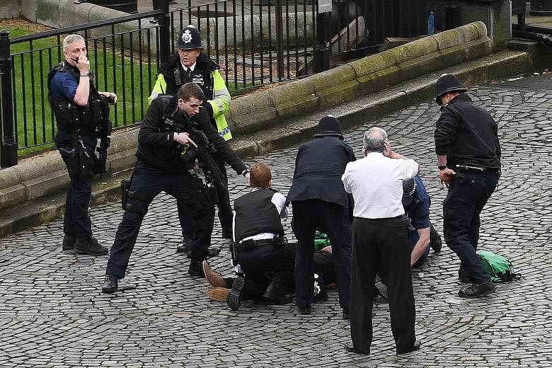 Police officers restraining an injured man, believed to be the attacker, outside the Palace of Westminster in London yesterday. The man allegedly ran into the compound with a knife and was confronted by police officers. He then reportedly stabbed one