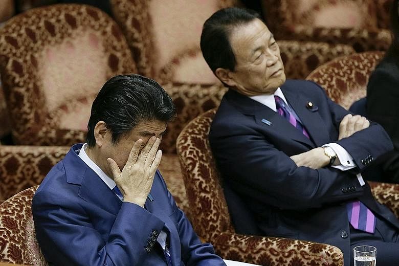 Mr Abe (left) and Finance Minister Taro Aso at an Upper House budget committee meeting in Parliament yesterday in Tokyo. Mr Aso said the land sale was completed with the proper procedures and pricing.