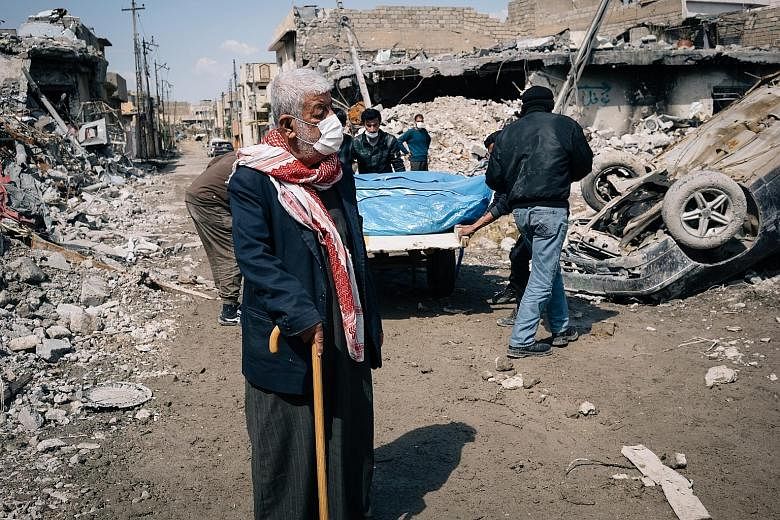 An elderly Iraqi reflects as bodies of civilians are carried out from the rubble of a bombed building in Mosul. Iraqi officials and witnesses say strikes in west Mosul have killed dozens of people in recent days, but the number of victims could not b