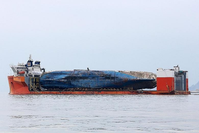 The Sewol ferry being carried on a semi-submersible transport vessel near Jindo yesterday after a salvage operation last week. It is expected to arrive at a major southern port as early as tomorrow.