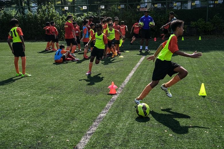 Children between the ages of five and 14 at a regular football training session conducted by the Yuhua Albirex Football Academy yesterday at Shuqun Secondary School. The organisation is run by Yuhua Community Sports Club, while S-League club Albirex 