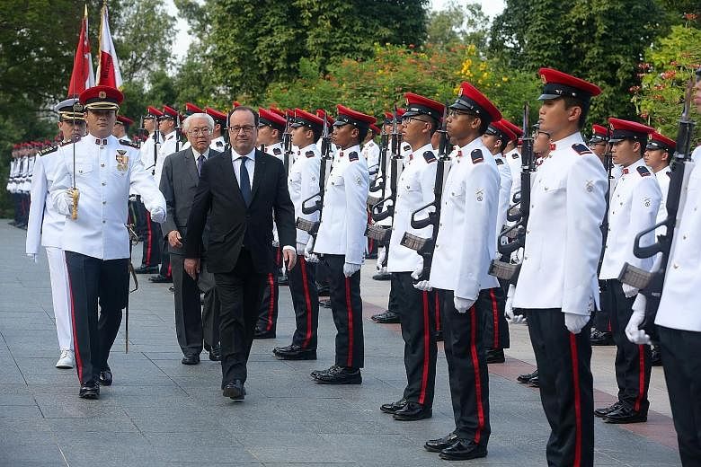 French President Francois Hollande inspecting the guard of honour with President Tony Tan Keng Yam at a welcome ceremony at the Istana yesterday. Mr Hollande is the first sitting French president to visit Singapore. Dr Tan and Mr Hollande at a state 