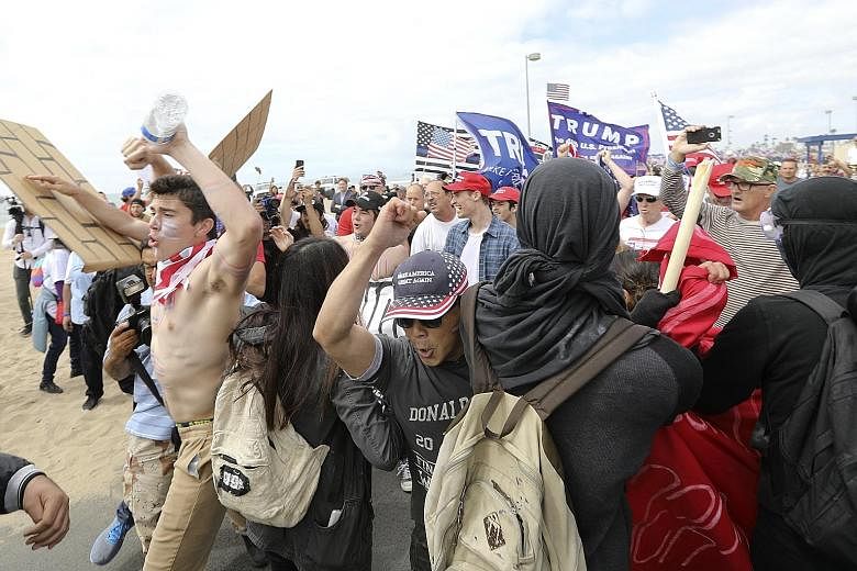 Trump supporters breaking through a human wall of anti-Trump protesters during a rally in Huntington Beach, California, last Saturday. Support for Mr Trump appeared unflagging despite the collapse of his campaign promise to overhaul the healthcare sy