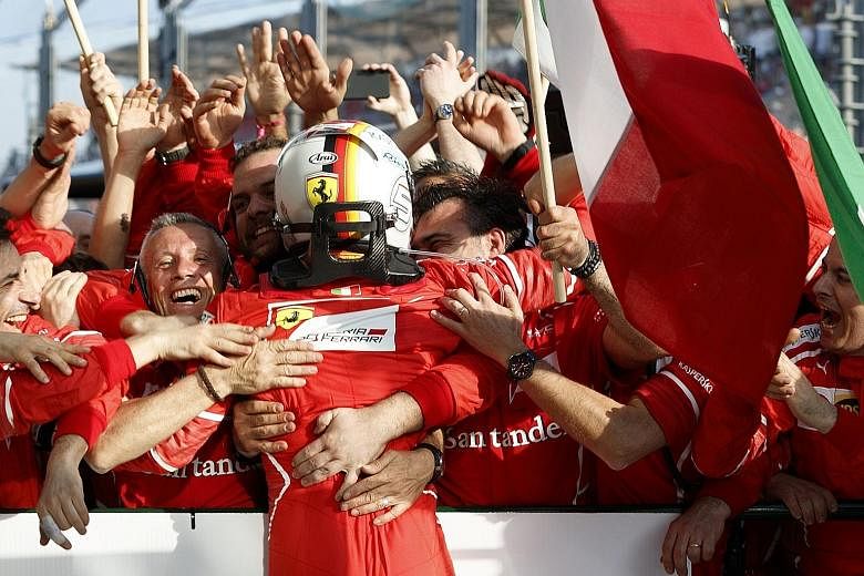 Ferrari driver Sebastian Vettel being mobbed by his team members after winning the Formula One season-opening Australian Grand Prix in Melbourne yesterday. The German beat Mercedes rival Lewis Hamilton by almost 10 seconds for his first race win sinc