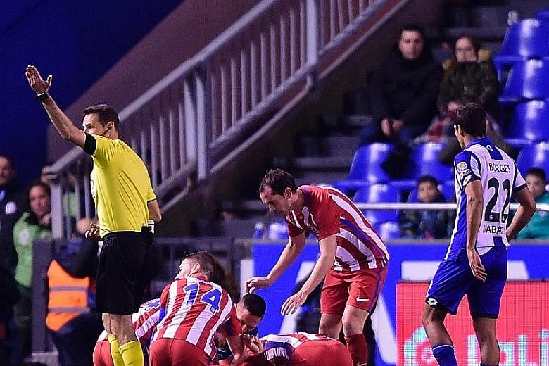 Teammates surrounding striker Fernando Torres, who suffered "traumatic brain injury" after a clash of heads on March 3.