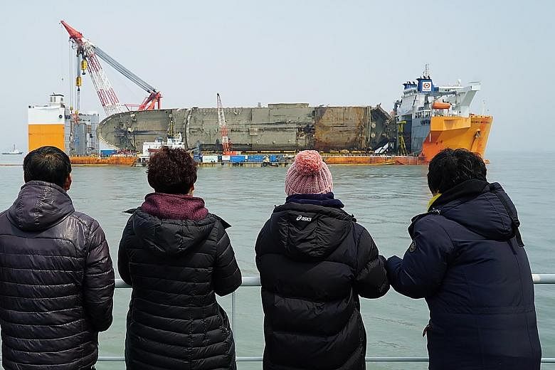 Relatives of the missing victims from the Sewol ferry disaster looking at the damaged vessel during a memorial service on a ship off the coast of the southern South Korean island of Jindo yesterday. The ferry sank nearly three years ago, with nine vi