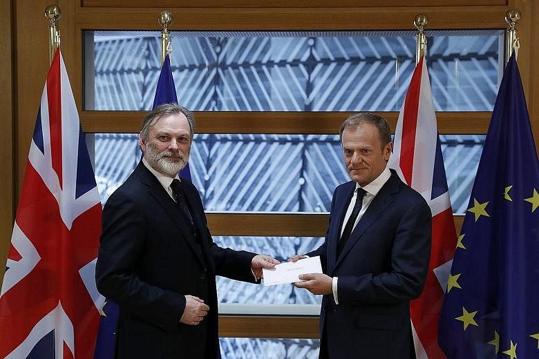 Britain's permanent representative to the European Union Tim Barrow (at left) delivering British Prime Minister Theresa May's Brexit letter to EU Council President Donald Tusk in Brussels yesterday.