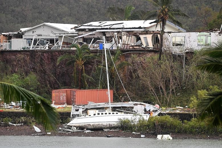 A boat seen smashed against the bank at Shute Harbour near Airlie Beach in north Queensland yesterday. Cyclone Debbie struck the Queensland coast at about midday on Tuesday, uprooting trees, washing boats ashore and ripping roofs off buildings. Farme