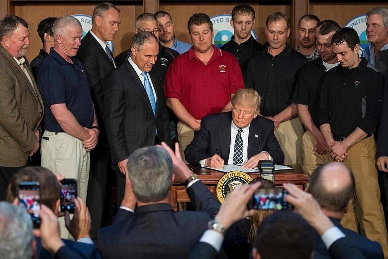 US President Donald Trump, surrounded by miners, signing the Energy Independence Executive Order at Environmental Protection Agency headquarters in Washington. The move has prompted international concern over the United States' commitment to fighting