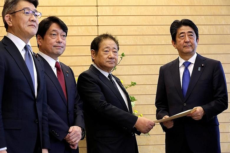 Mr Abe receiving a proposal on missile defence from Mr Hiroshi Imazu, chairman of the Research Commission on Security of Japan's ruling Liberal Democratic Party, who is accompanied by former defence minister Itsunori Onodera at the Prime Minister's O
