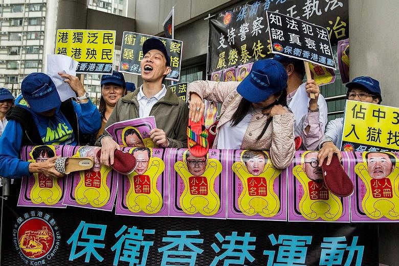 Pro-government protesters using slippers to beat pictures of the leaders of the Occupy Central movement outside the Eastern District Court yesterday. Nine activists involved in the 2014 protests were charged yesterday.
