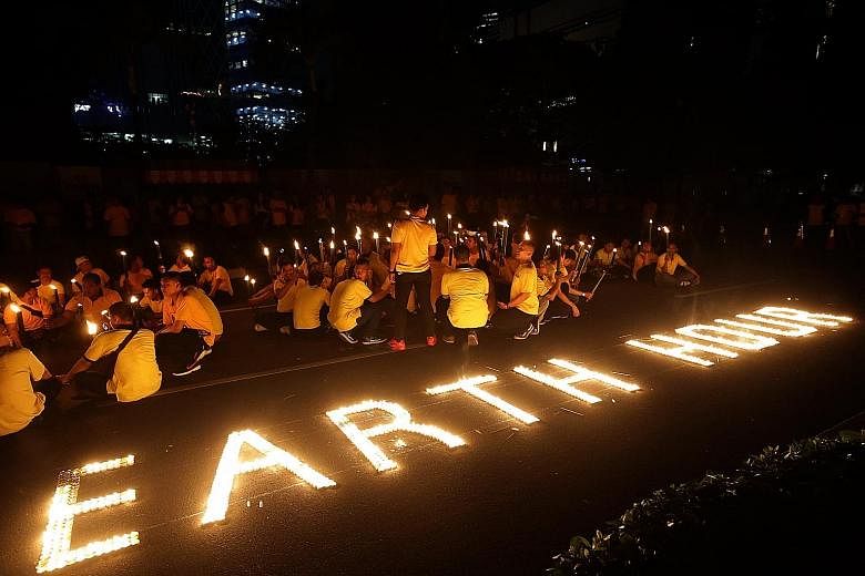 Workers in Indonesia at a candlelit event to mark Earth Day in Jakarta last Saturday when the city dimmed some of its lights for an hour. Regulations for promoting energy efficiency, if poorly thought out, can be costly and unintentionally cause larg
