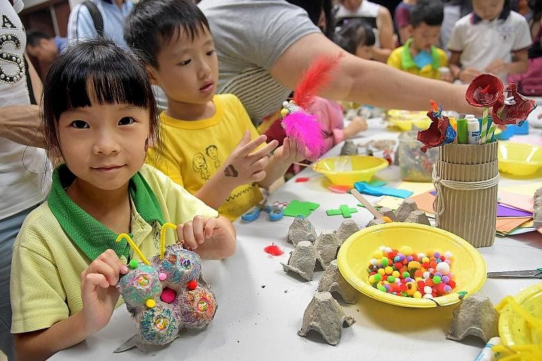 Yu Zi Xing, six, with a butterfly she made from recycled materials at the Recycling Carnival yesterday, which featured games and crafts stations made out of recycled materials.