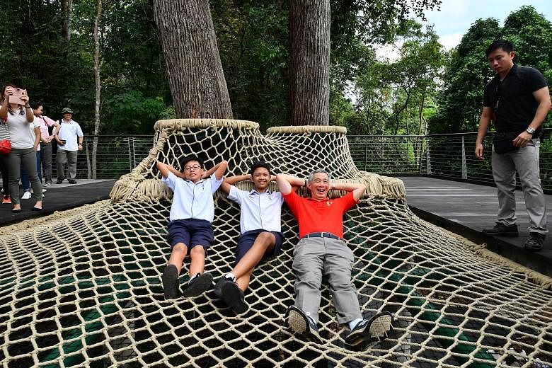 Tanglin Secondary School students Casey Lim and Muhammad Nabil Ali joining PM Lee on the Canopy Web yesterday at the SPH Walk of Giants, an elevated boardwalk that is part of the Botanic Gardens' new Learning Forest. The forest will be a new zone for