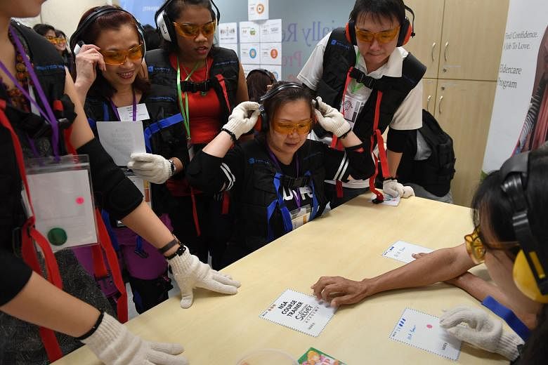 Madam Wendy Teo adjusting her ear mufflers at the workshop, where she and her fellow participants donned a heavy vest, glasses and mufflers to simulate old age. Workshops like this are part of the Eldercare Program, which prepares low-income women and sin